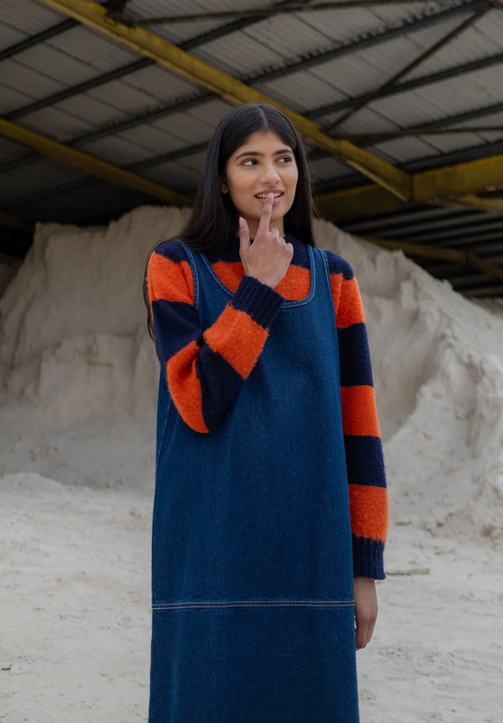 Woman wearing a Folk blue Slip Dress with orange and navy accents in an industrial setting.